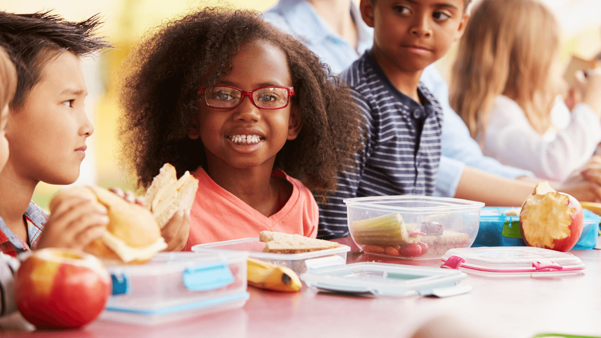 Smiling girl eating her lunch with friends